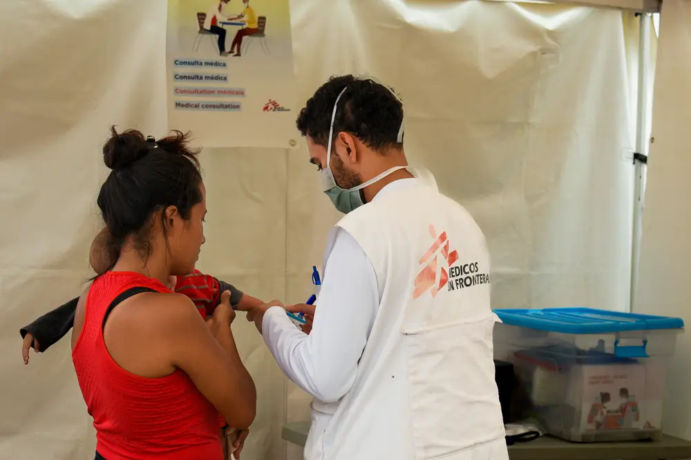 un enfermero de la clínica móvil de MSF revisa a una mujer, cuyo bebé tiene fiebre y diarrea aguda. En la clínica móvil atencíon a migrantes en su paso por Honduras