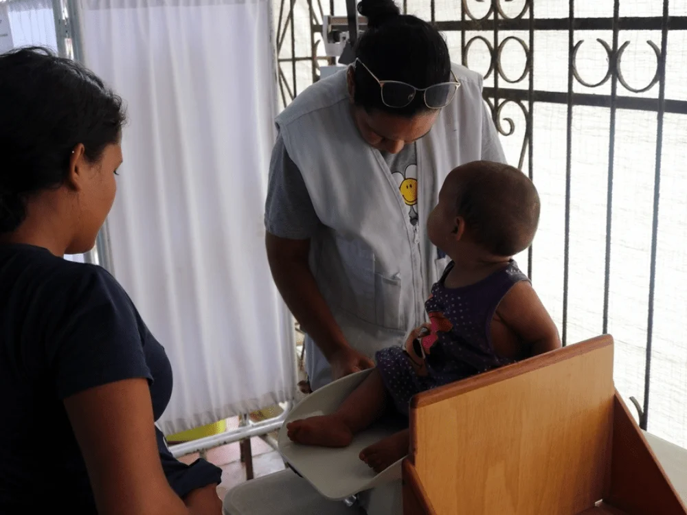 Personal de enfermería de MSF pesa y mide a una bebé que llegó con su familia hasta el puesto de salud de MSF. © MSF