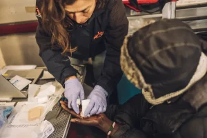 Personal de Médicos Sin Fronteras hace curación en la mano de un migrante menor no acompañado