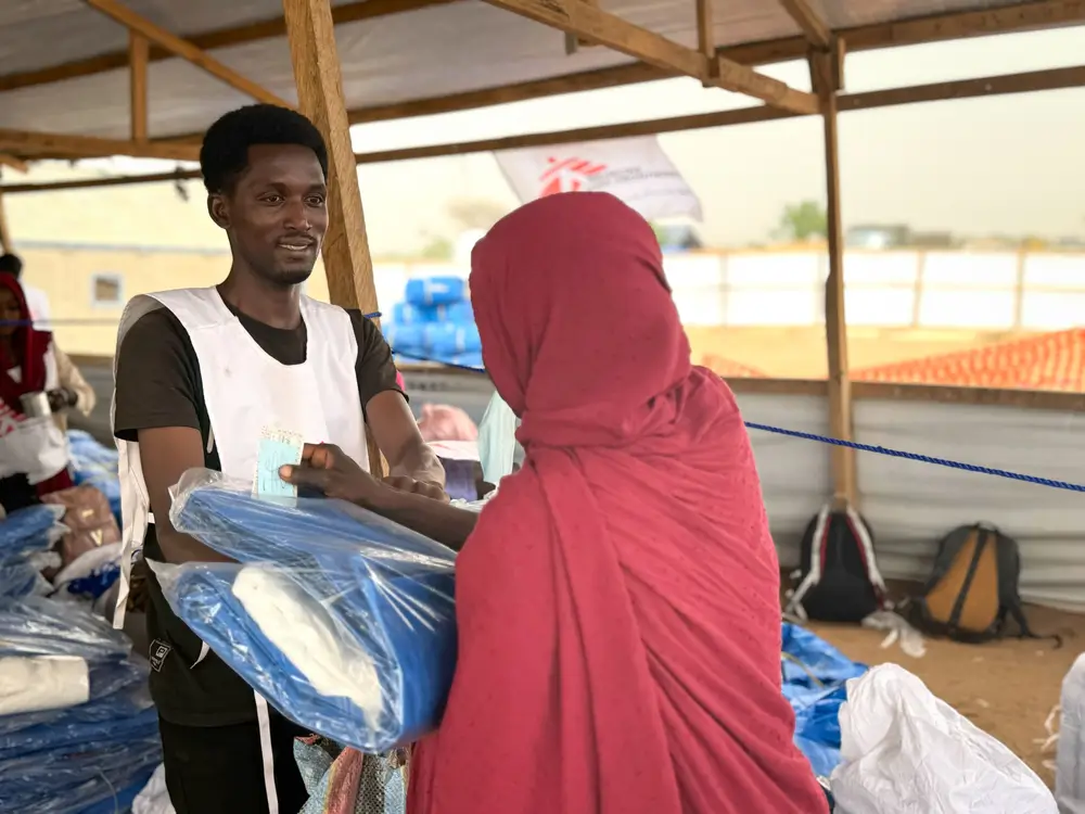 Personal de Médicos SIn Fronteras entrega un kit a una  mujer refugiada en el campo de Adré
