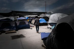 Un hombre caminando entre las tiendas de campaña de un campamento para personas migrantes en Reynosa.