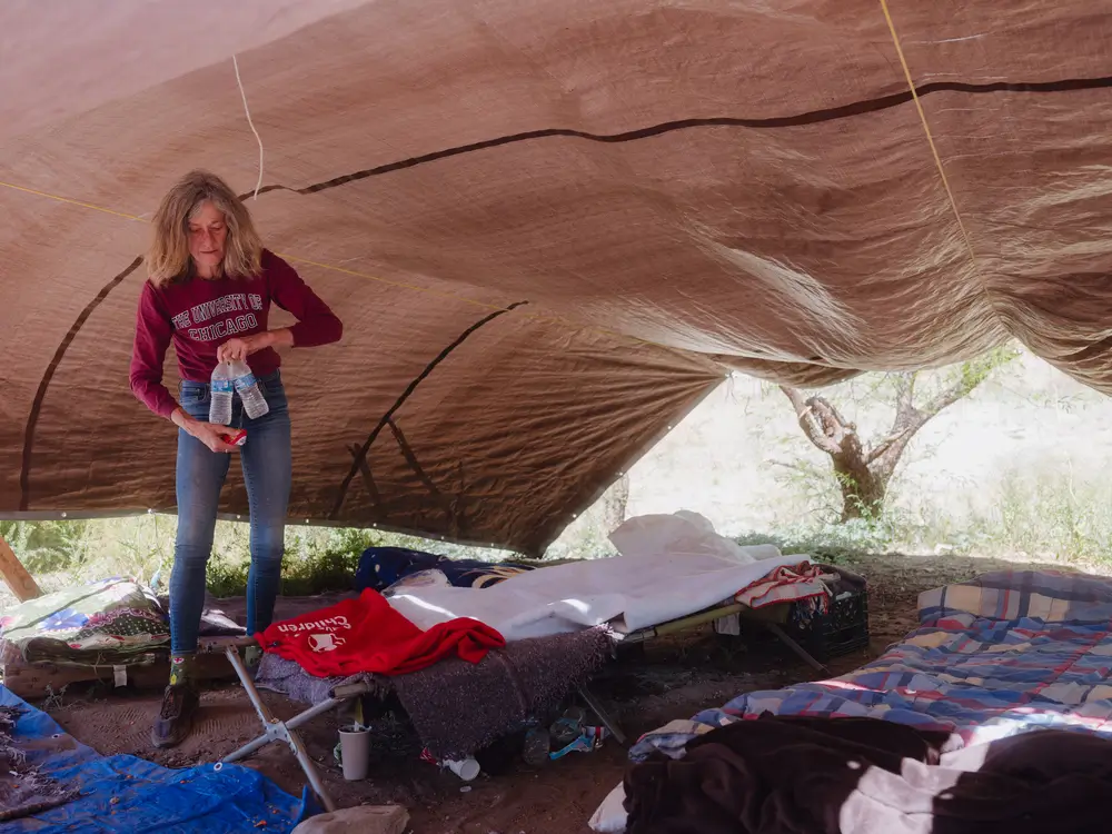 Christy, integrante de Tucson Samaritans, ayudando a recoger un catre en un campo improvisado en Sasabe, Arizona.