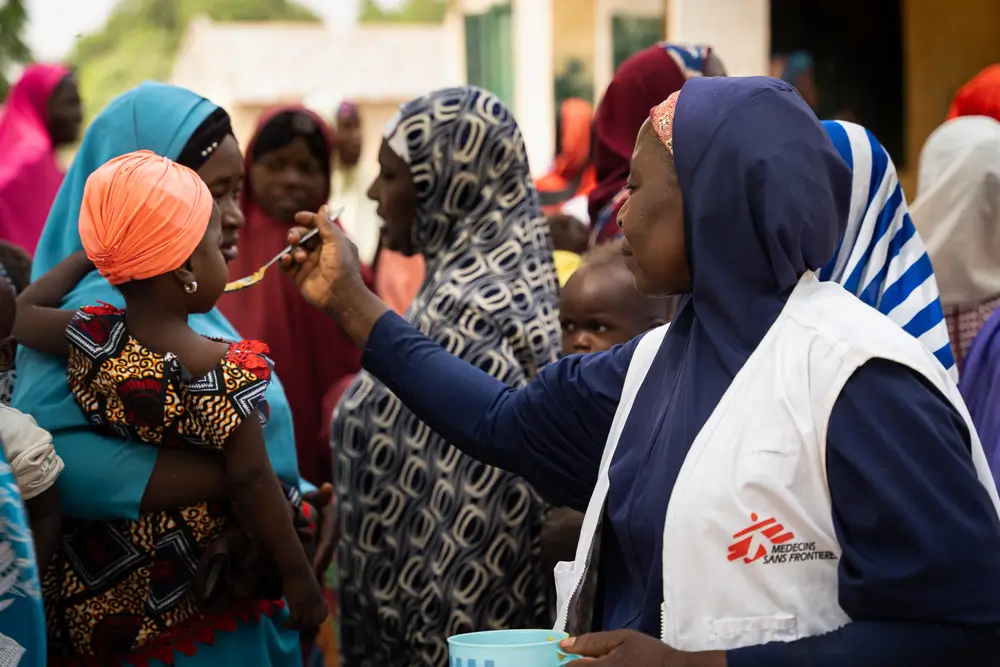 Maryam Muhammad, de MSF en Kebbi, entrega una cuchara de Tom Brown a un niño durante una demostración de la receta para la desnutrición en Maishaka, Nigeria.