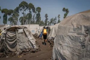 Una mujer cargando un bidón de agua por un campo de personas desplazadas en Goma, República Democrática del Congo.