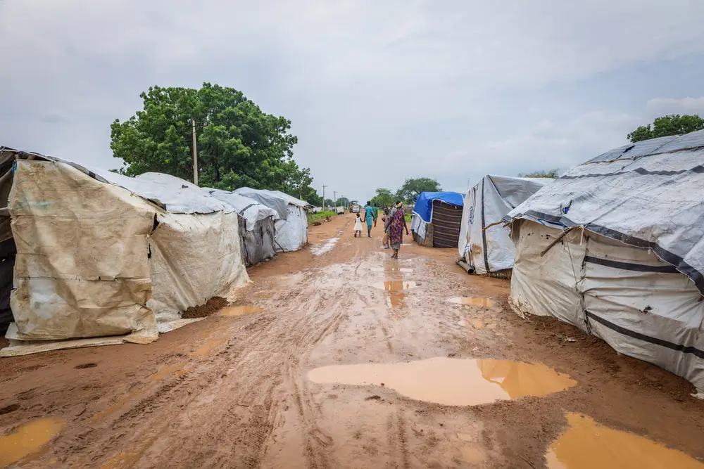 Vista de una carretera en Abyei donde las familias desplazadas por las inundaciones están construyendo refugios hechos con palos pequeños y láminas de plástico.