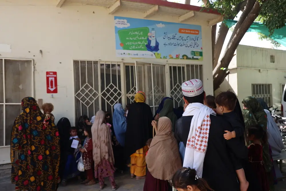 Padres y madres esperan fuera de la sala de registro para inscribir a sus hijos para la consulta en el centro de salud materno infantil de MSF en Kuchlak.