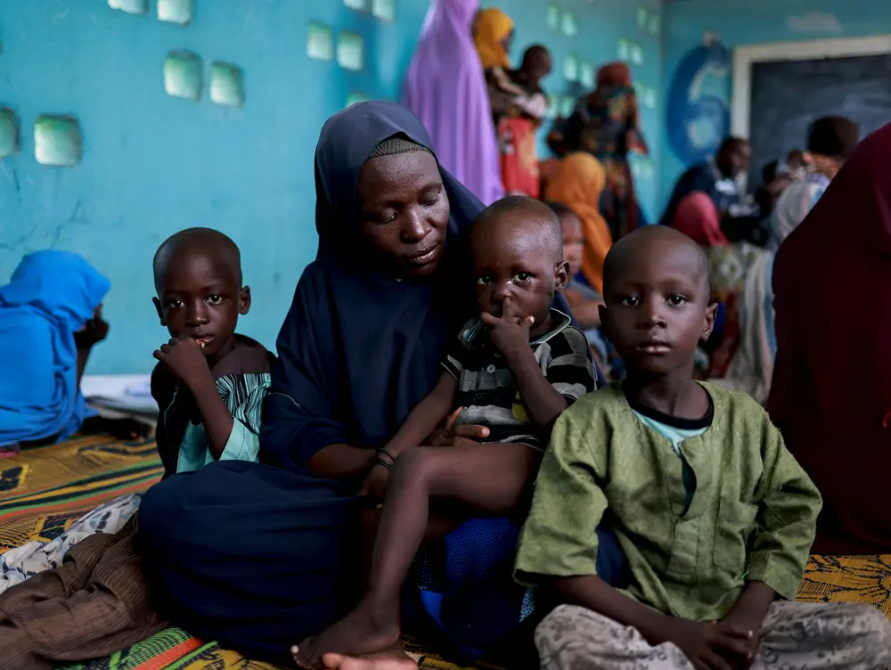 Baana y sus hijos sentados en la clínica móvil de MSF en el campamento de Teachers Village, en Maiduguri, Nigeria.