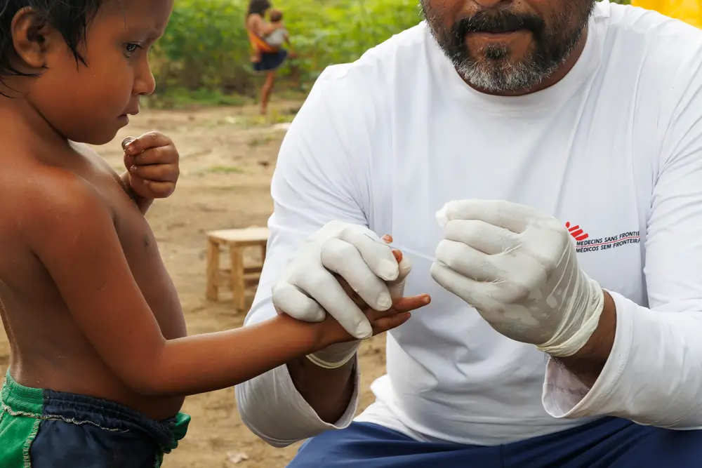 Un miembre de Médicos SIn Fronteras realiza una prueba de malaria a un niño yanomami.