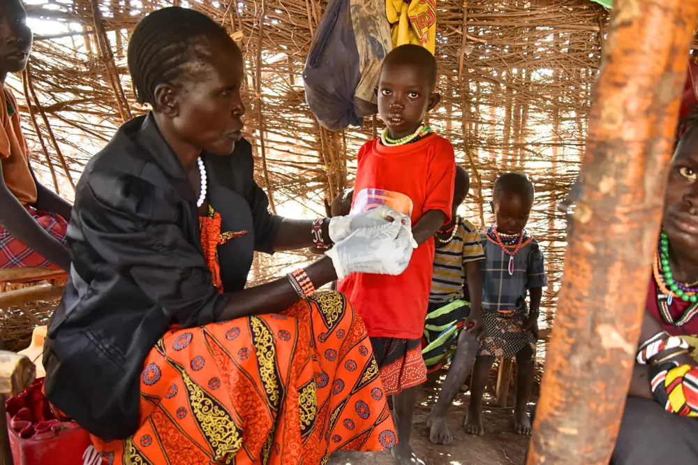 La promotora de salud comunitaria, Elizabeth Lowiale, examina a Kang’usu Domong’iro, de 3 años, para detectar malaria en su casa mientras su madre, Cheparkeno Domong’iro, observa. Baringo, Kenia.