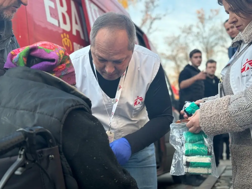 El médico de MSF Oleksandr Hontariev realiza un tratamiento quirúrgico inicial en el brazo de un paciente. Cerca del centro de tránsito, donde tenemos nuestra clínica móvil