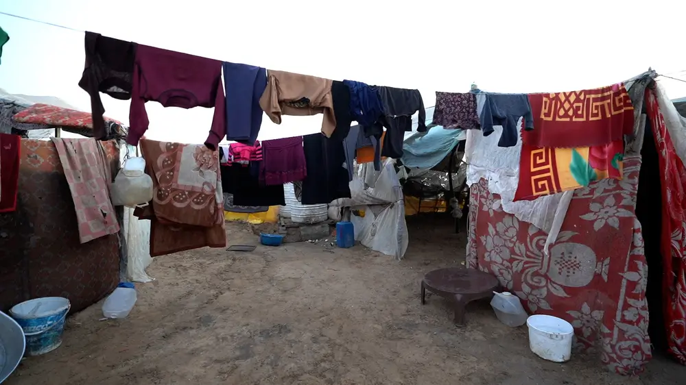 En el interior de una frágil tienda de campaña hecha con mantas y láminas de plástico finas cuelgan dos túnicas con ropa secándose sobre ellas. enfrentándose a la escasez de ayuda humanitaria. 