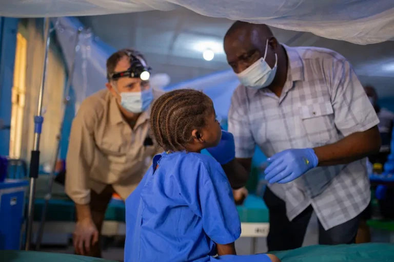 El Dr. Kefas y el Dr. Dave examinan a una niña con noma (ETD) que se sometió a una cirugía reconstructiva que le cambió la vida. Nigeria, octubre de 2023.