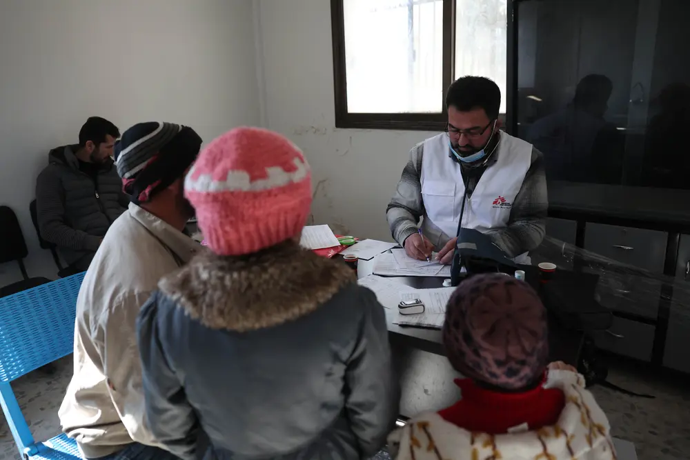 Mohammed Gobasi, trabajador médico de MSF, proporciona una receta a un padre con sus dos hijos en las clínicas móviles de MSF en Guta Oriental. © Omar Haj Kadour