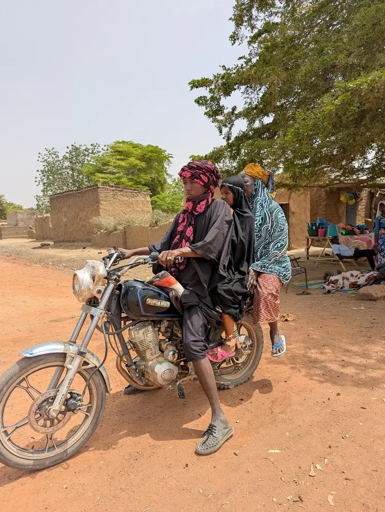 En motocicleta, una mujer embarazada, acompañada de su partera tradicional, se dirige al centro de salud N8 en Niono para dar a luz con el apoyo de MSF.