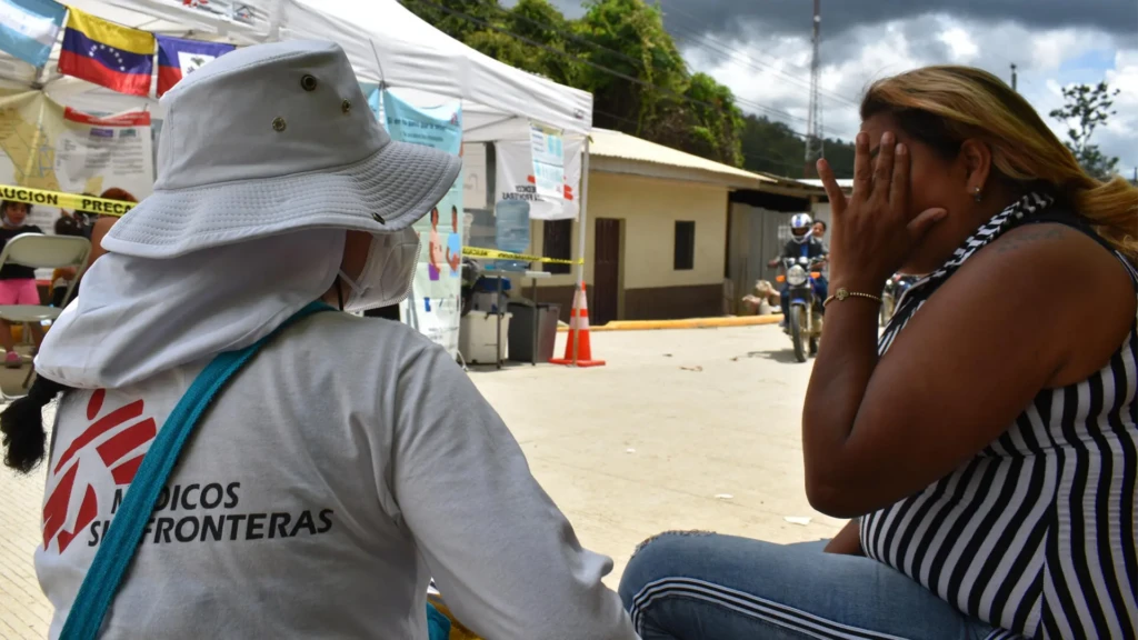 Una de las promotoras de salud escucha la plática de la familia Brito sobre cómo fue su experiencia por el Darién.