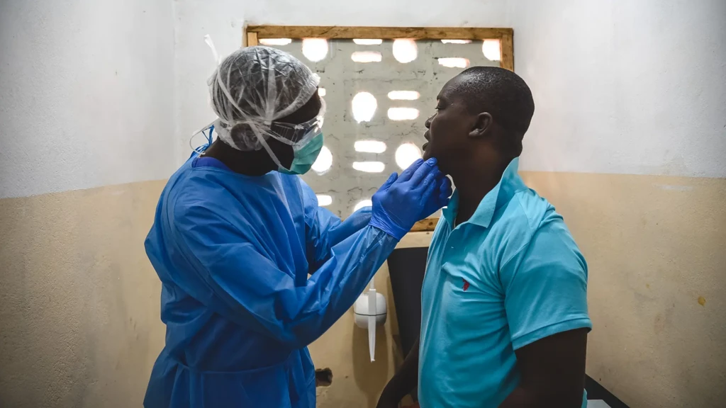 George Kamara, oficial de salud comunitaria de MSF, examina a un paciente dentro del centro de tratamiento mpox en la ciudad de Calaba, Freetown, Sierra Leona, junio de 2025.