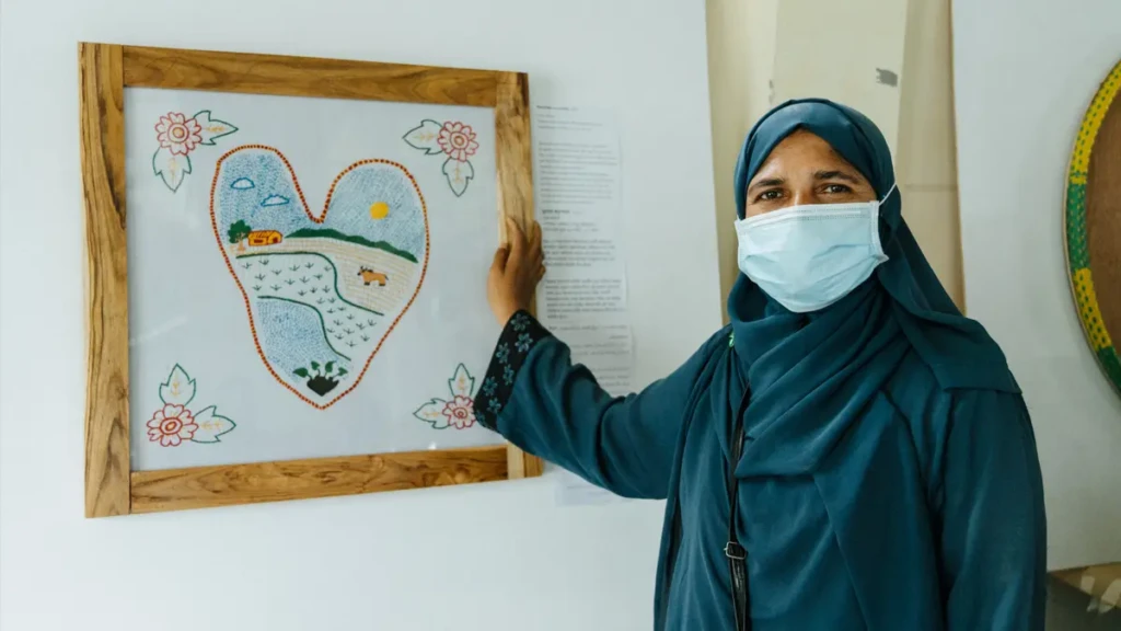 Senu Anara, refugiada rohingya junto a su obra, dibujo de una hoja de taro. “Nunca pensamos que los gobiernos de Rakáin y Myanmar nos expulsarían. La hoja de taro es nuestro documento y nosotros somos el agua. Si mostramos esto al mundo, tal vez nuestra huella perdure”. Senu Anara, refugiada rohingya. Bangladesh © Victor Caringal/MSF