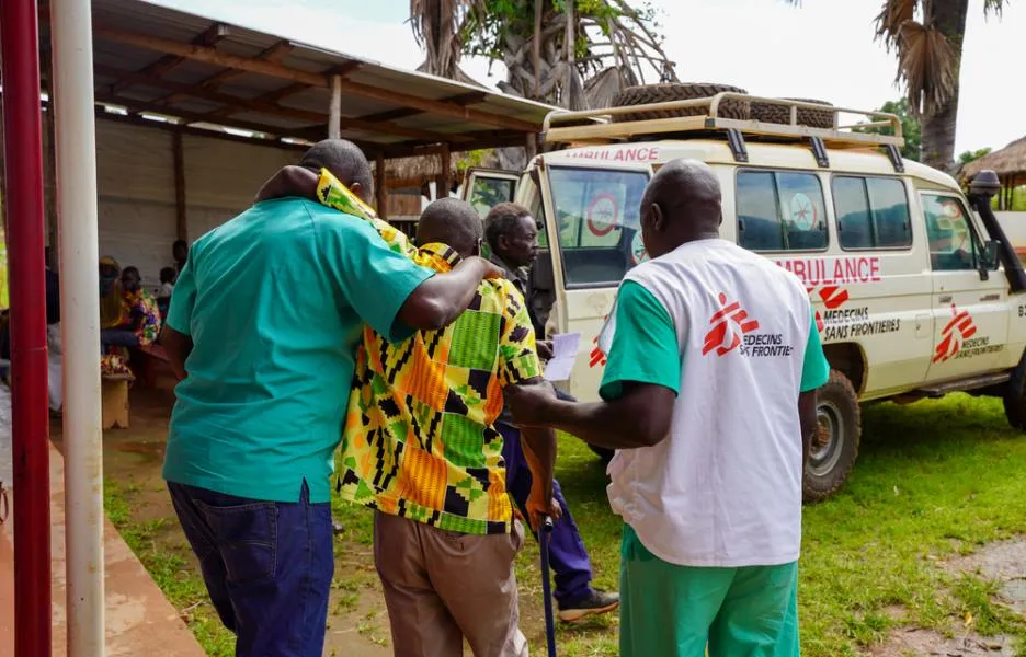 Dos miembros del personal médico de MSF ayudan a un paciente a llegar a la ambulancia en la clínica Jansuk, condado de Yei, Ecuatoria Central.