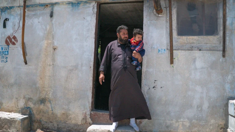 Walid y su hijo menor fuera de su refugio en el campamento de Al-Kuwaiti, Idlib, al noroeste de Siria.