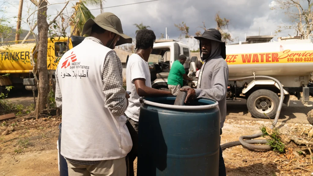 Lal Badshah, responsable de agua y saneamiento supervisa el llenado de un tanque de agua de 200 litros en la parroquia de Santa Isabel. La parroquia aún carece de electricidad y la infraestructura hídrica sigue interrumpida.