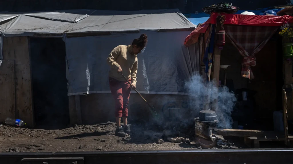 Carmen limpia el exterior de su “ranchito” en el barrio de Vallejo, el lugar que ha sido su hogar durante los últimos meses luego de que ya no pudiera continuar su viaje a Estados Unidos en busca de una vida con más oportunidades y seguridad para ella y su familia. © Yael Martínez/Magnum Photos