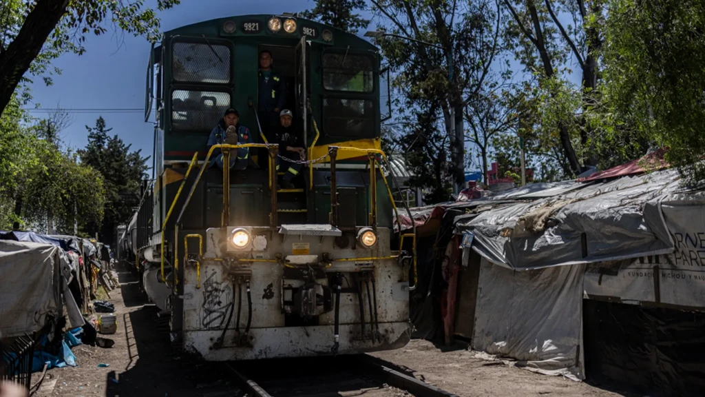 El tren pasa por las vías del barrio Vallejo dos veces por semana, lo que obliga a la gente del campamento a recoger sus pertenencias y entrar a sus casas para que el tren no los atropelle. © Yael Martínez/Magnum Photos