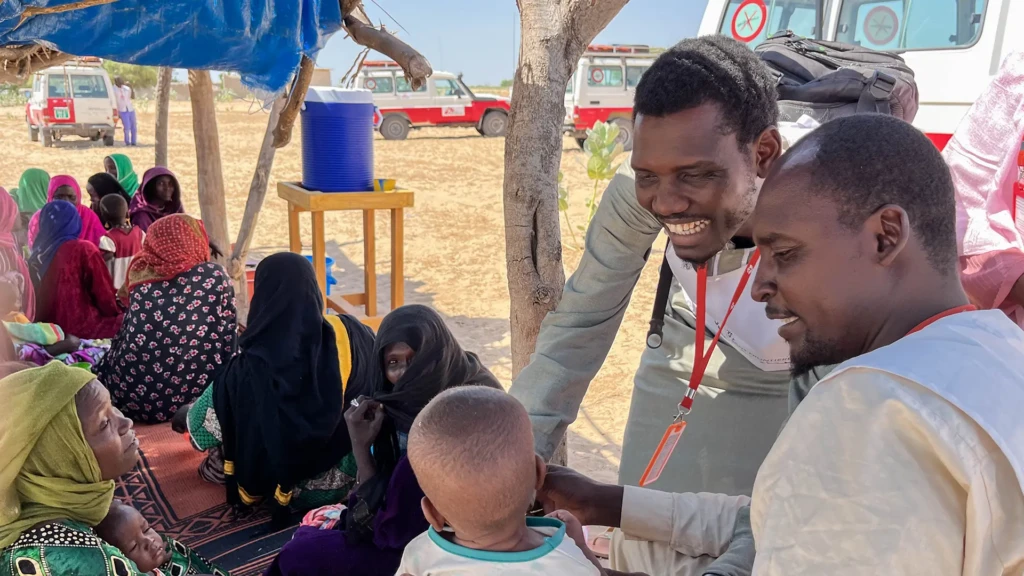 Las mujeres y sus bebés esperan para recibir una consulta. Cherif Mohamat Adoum (a la derecha), es un promotor de la salud de MSF que supervisa la actividad. 