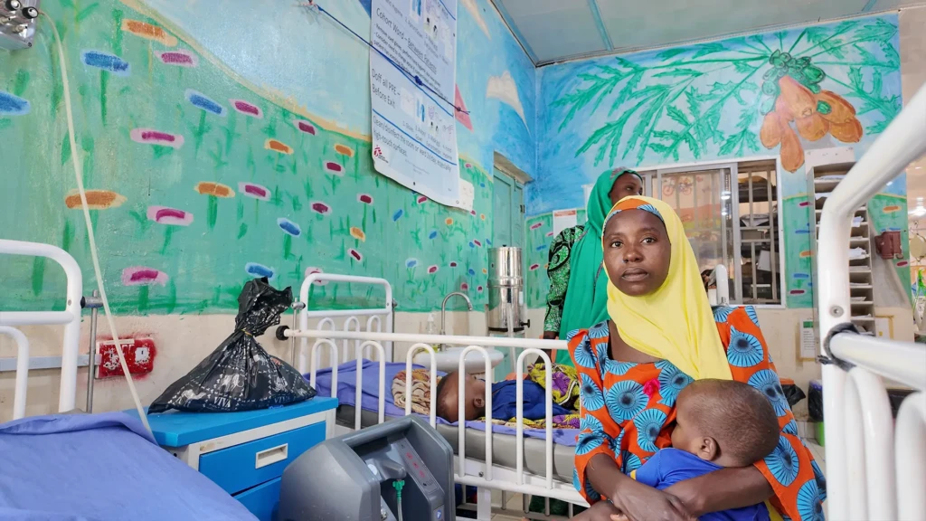 Amina Lawali se sienta junto a su hijo Yusufa mientras se recupera de una malaria grave en el hospital de Gummi, apoyado por MSF. Fue ingresado con fiebre alta y convulsiones tras ser derivado desde un centro de salud cercano.