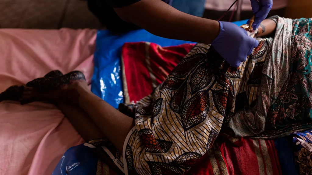 Amina Tahila, una madre primeriza, se acuesta en la cama con su bebé y un kit gratuito de elementos esenciales para el cuidado posparto proporcionado por MSF para las nuevas madres que dan a luz en el Hospital General Shinkafi.