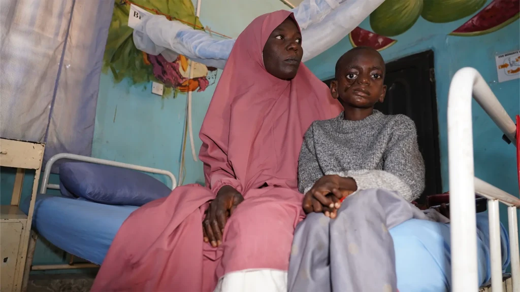 Shafa Saidu y su hijo, Umar Saidu, un paciente de noma, sentados dentro de una sala del Hospital Infantil Noma (NCH) en Sokoto, Nigeria.