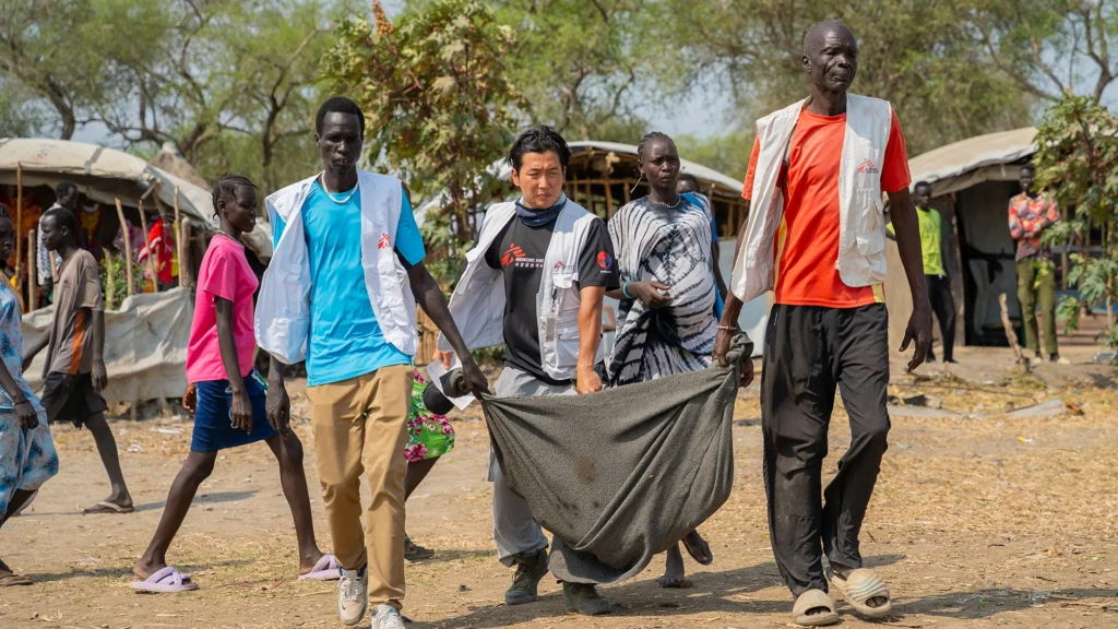 Los equipos de MSF derivan a un paciente con heridas graves desde Yakuach a Chuil, estado de Jonglei, Sudán del Sur, llevándolo en una manta hasta un barco para trasladarlo a la clínica para recibir atención.