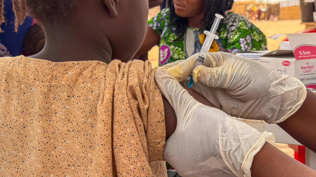 Mujeres y niños se reúnen en un punto de vacunación en un asentamiento de refugiados en Adré, donde el hacinamiento y la inmunización rutinaria limitada aumentan el riesgo de transmisión del sarampión.