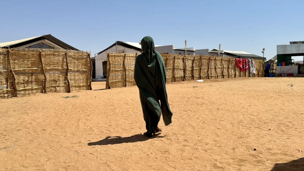 Halima* se encuentra frente a refugios improvisados ​​en Tawila. Mientras huía de El Fasher, Halima fue interceptada por hombres armados, antes de escapar con su hermana. Darfur Norte, Sudán, febrero de 2026.