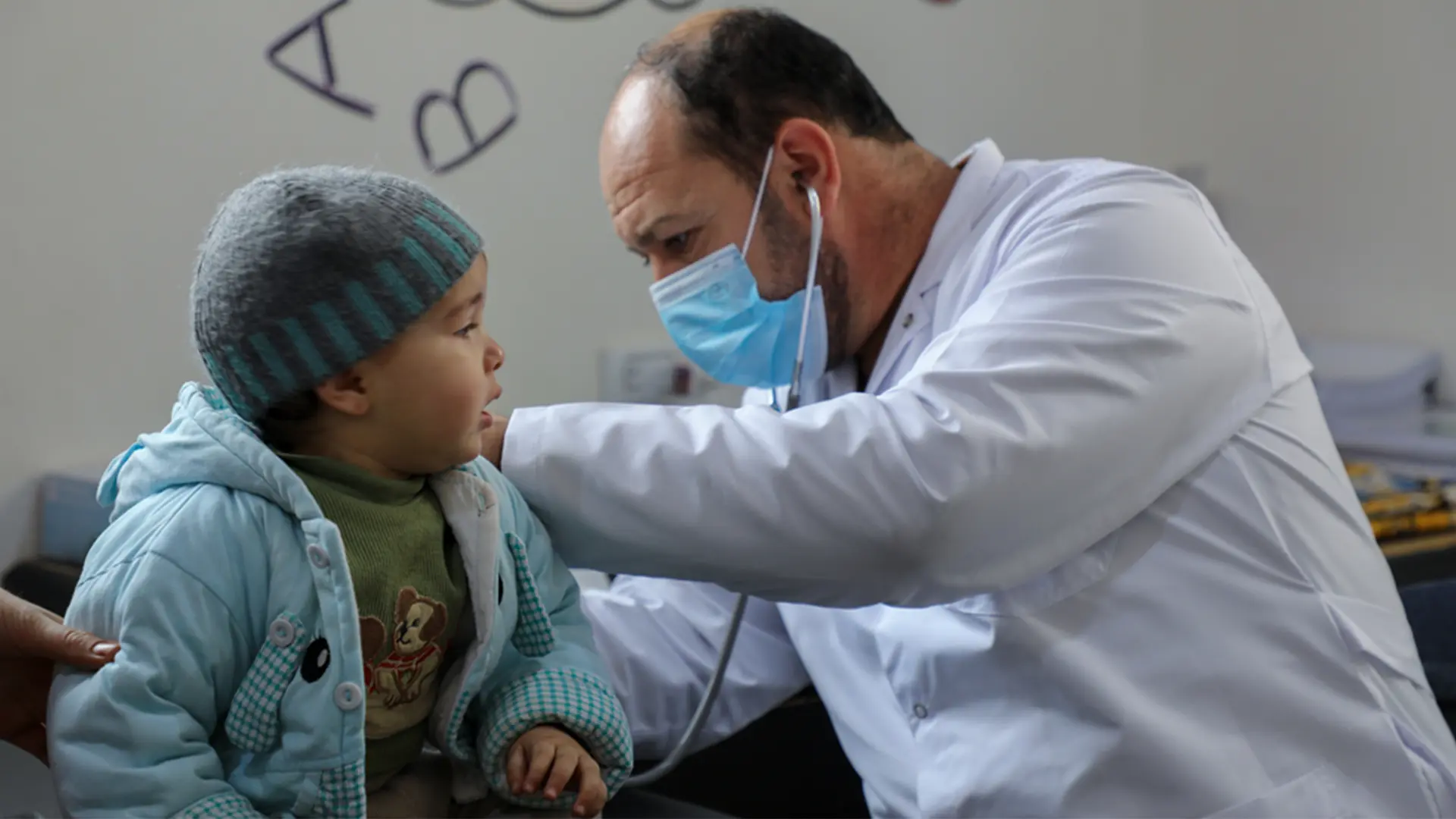 Un médico de la Dirección General de Salud examina a un niño en el centro de atención primaria de Darat Ezza, que cuenta con el apoyo de Médicos Sin Fronteras.