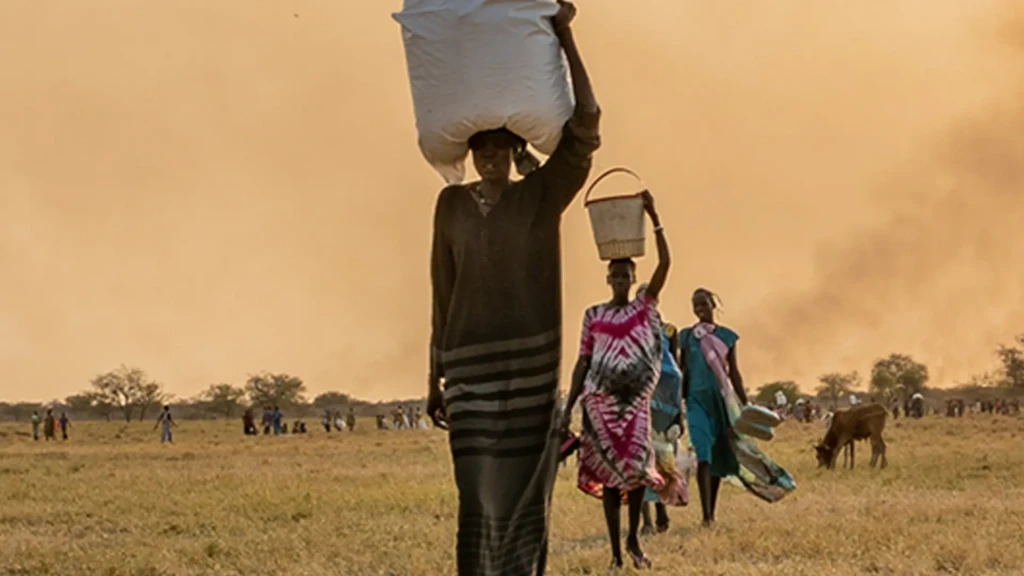 Una mujer lleva bolsas de comida en la cabeza tras un lanzamiento aéreo del PMA cerca de Chuil, estado de Jonglei, Sudán del Sur. La escalada de la violencia ha desencadenado una nueva ola de desplazamientos.