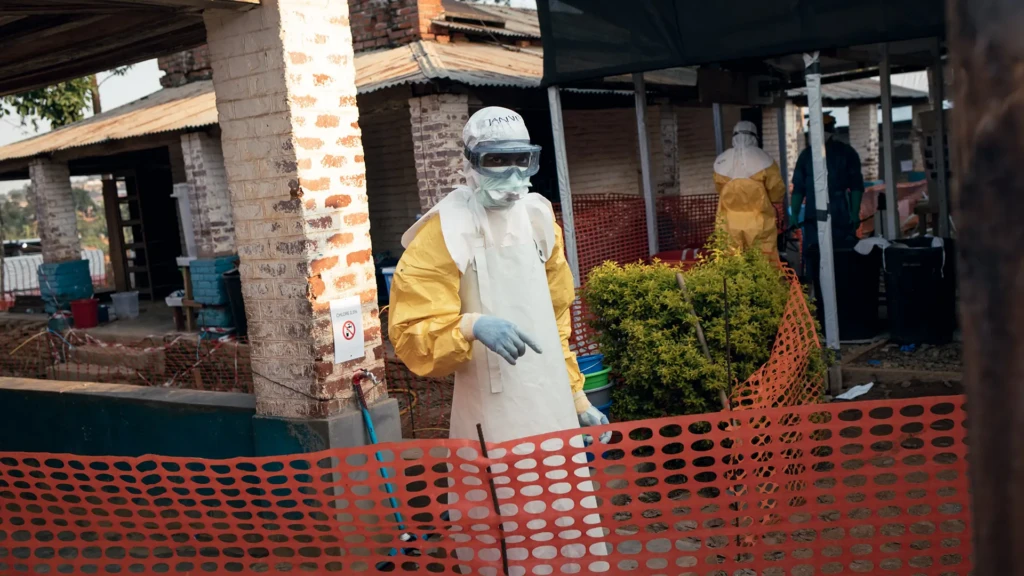 Un miembro del personal de MSF se comunica desde la zona de alto riesgo con colegas destinados en la zona de bajo riesgo del Centro de Tratamiento del Ébola del Hospital General Mongbwalu. Mongbwalu, provincia de Ituri, República Democrática del Congo, 17 de junio de 2026.