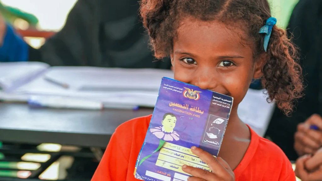 Una niña de 5 años sostiene felizmente su tarjeta de vacunación tras asistir a una actividad de vacunación contra el sarampión en Ateera (2), distrito de Tuban, gobernación de Lahj, Yemen, el 5 de mayo de 2026.