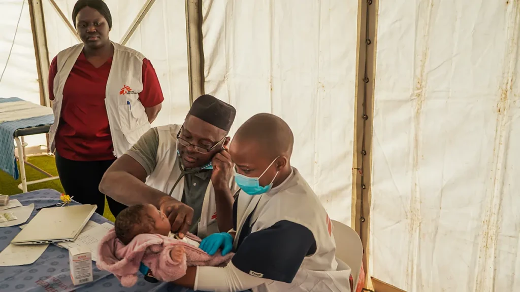 El médico de MSF Adebayo Mikail Abisola y la enfermera Silindelwe Khanyile revisan las constantes vitales de un bebé en la clínica de urgencias de MSF en Musina, Sudáfrica