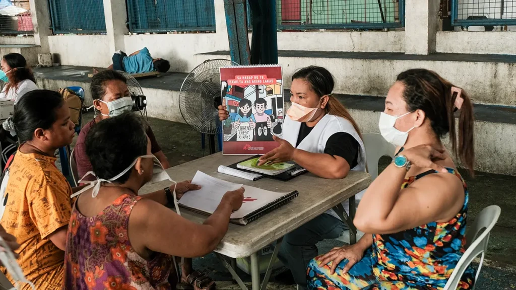 Girlie Manong, miembro del personal de MSF que trabaja en la búsqueda activa de casos, explica una infografía de tuberculosis a los pacientes en Tondo, Manila. Filipinas, octubre de 2025.