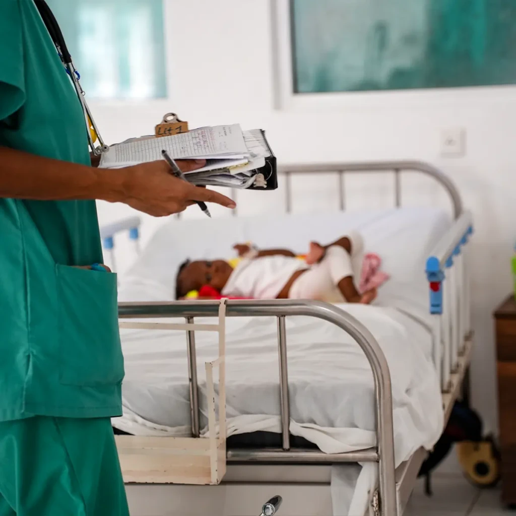 Una enfermera pasa junto a la cama de un niño en la sala de pediatría del hospital Cité Soleil. Ubicado en una vasta zona aislada de Puerto Príncipe, controlada por completo por grupos armados, este centro de salud es el único accesible para los miles de habitantes de la zona.