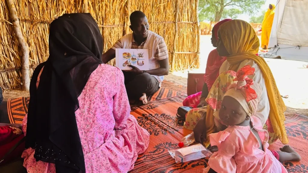 Un Supervisor de Promoción de la Salud de MSF, sensibiliza a las madres sobre las prácticas de higiene mientras esperan su consulta en la clínica móvil instalada en el centro de tránsito de Adémour, en la provincia de Sila, Chad.