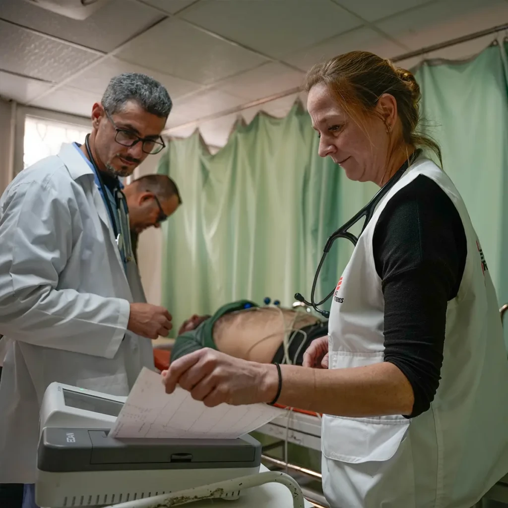 Maya, responsable de actividades médicas de MSF, y Raed, enfermera de la dirección de salud, revisan los resultados del ECG (electrocardiograma) del paciente en la sala de urgencias del Hospital Nacional de Sweida.