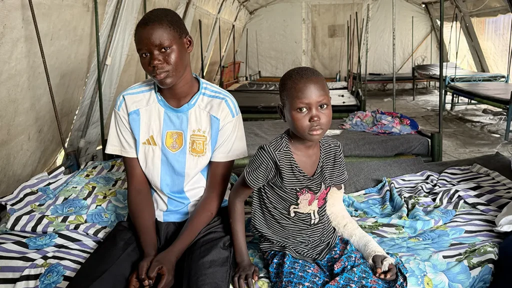 En la sala de espera reservada para pacientes dados de alta, Aben (18) y su hermana Nyambol (7) esperan el transporte para llevarlas de vuelta a su hogar a orillas del río Sobat.