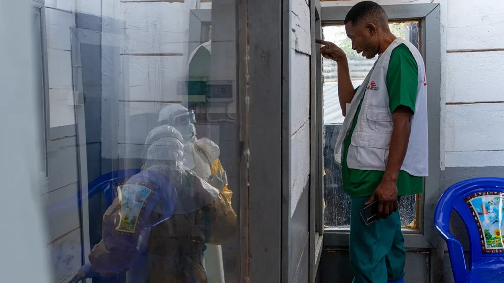 El responsable de las actividades médicas de MSF, guía un equipo médico entrante en la zona de premios a cargo de los sospechosos en el CTE de Kitatumba.