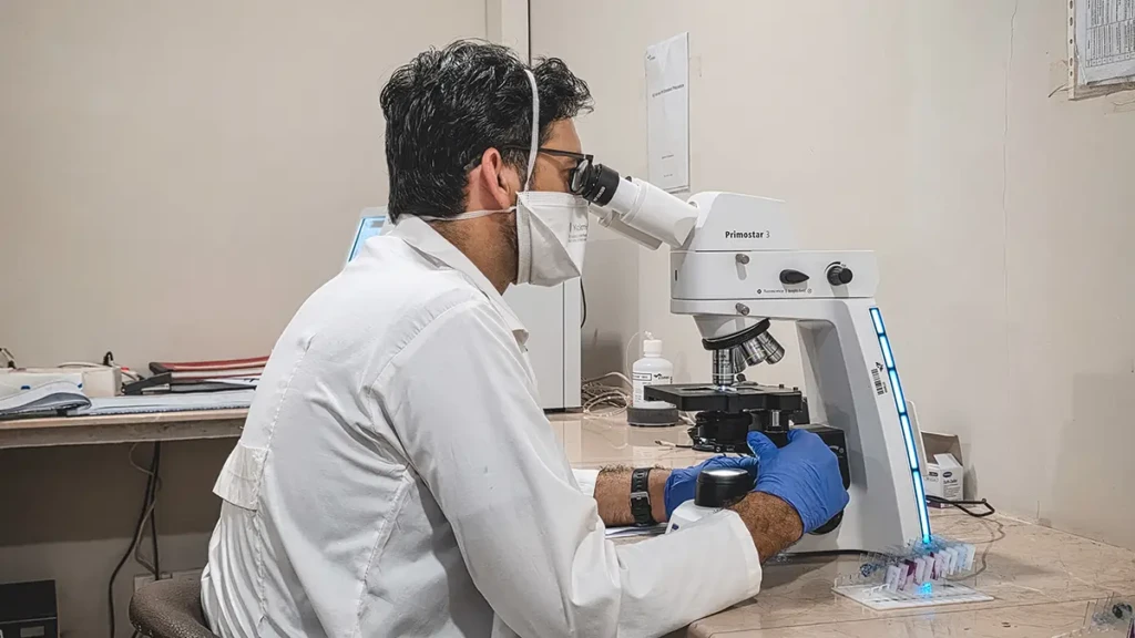Un técnico de laboratorio de MSF examina una muestra bajo un microscopio en la clínica de TB de MSF en el Centro de Salud Rural Baldia en Karachi.
