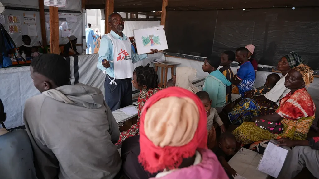 En la sala de espera de un puesto sanitario en el campo de refugiados de Busuma, un personal de MSF sensibiliza a los pacientes sobre diversos problemas de salud y los servicios disponibles, incluido el apoyo psicológico.
