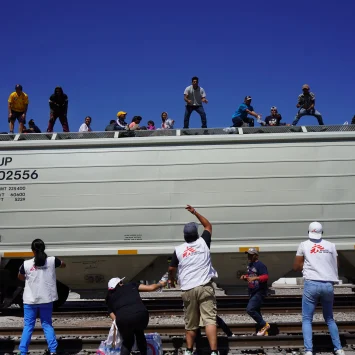 Personal de Médicos Sin Fronteras apoya en la distribución de agua a personas migrantes a bordo de un tren, en su ruta migratoria hacia Estados Unidos