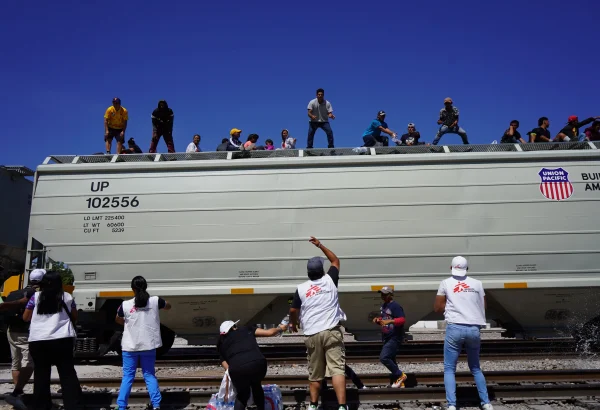 Personal de Médicos Sin Fronteras apoya en la distribución de agua a personas migrantes a bordo de un tren, en su ruta migratoria hacia Estados Unidos