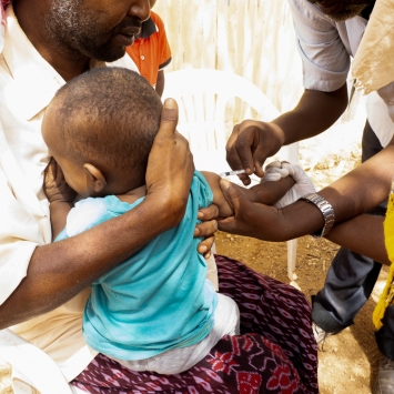 Ali Ibrahim sosteniendo a su hijo mientras es vacunado contra el sarampión en Burao. © Mohamed Hussein (MOTO)/MSF