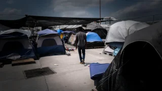 Un hombre caminando entre las tiendas de campaña de un campamento para personas migrantes en Reynosa.